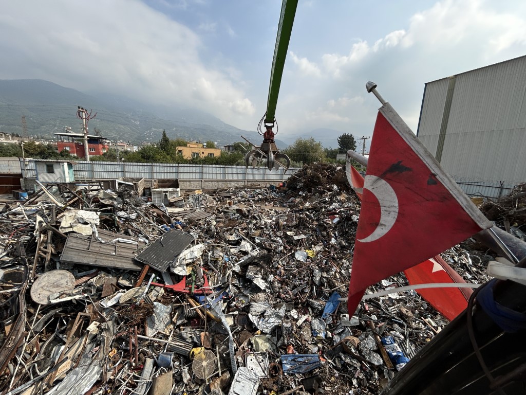 Hurda yığını içerisindeki Türk bayrağını elleriyle çıkararak iş makinesine astı