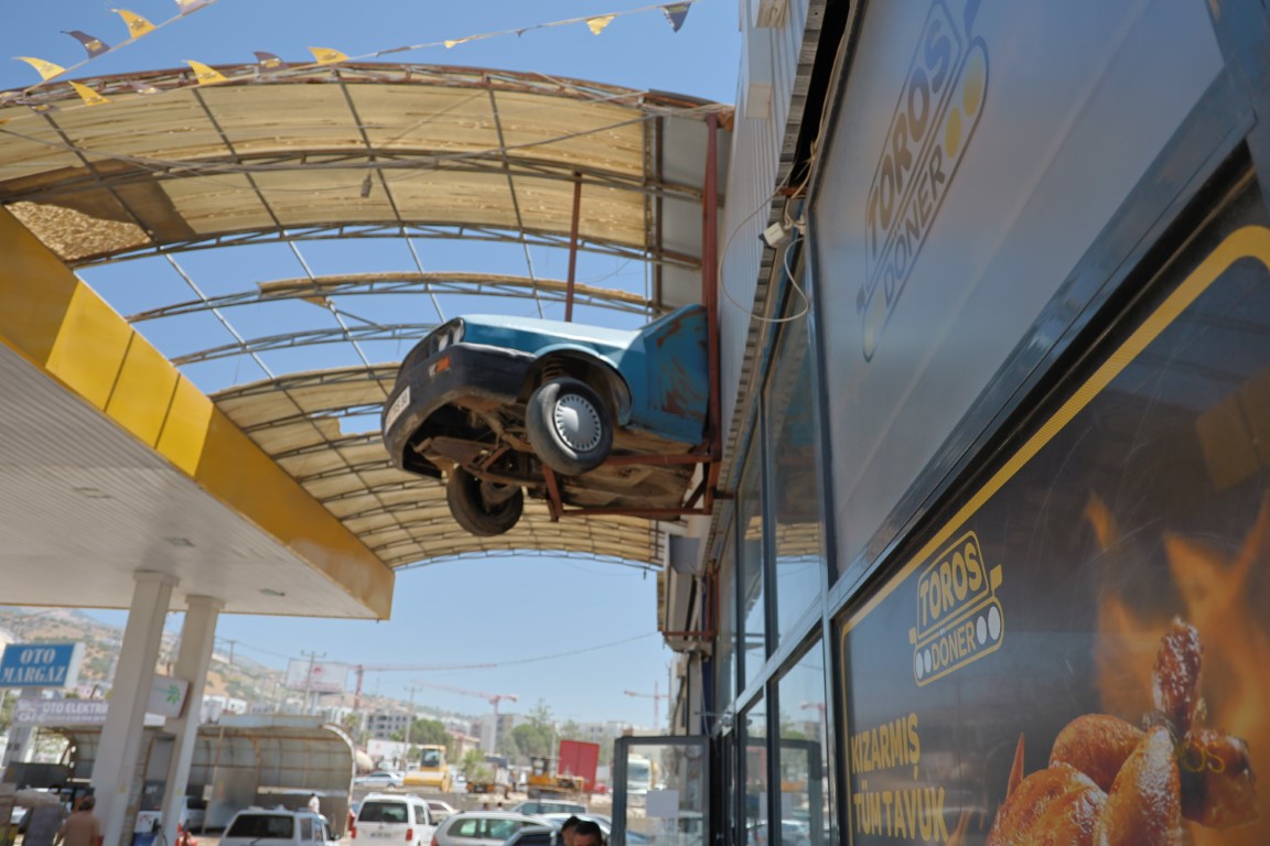 Depremde yarısı enkazda kalan otomobilin geriye kalan kısmını dükkanına astı