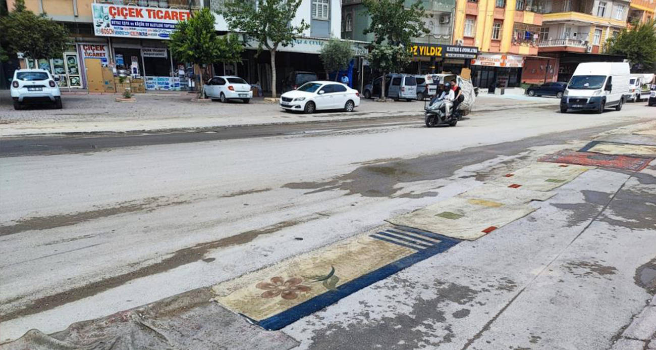 Adana’da belediyenin yapmadığı yola esnaftan ilginç çözüm: Yola asfalt yerine halı serildi