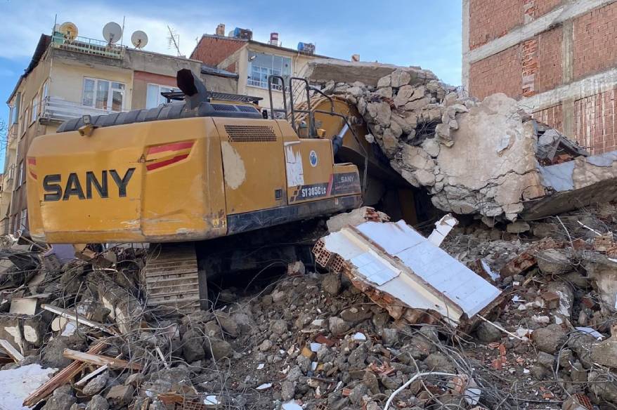 Ağır hasarlı binanın enkazı iş makinesinin üstüne yıkıldı