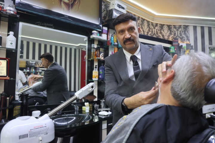 Mesleğine olan ciddiyetini kaybetmeyen berber, yaz kış demeden müşterilerini takım elbiseyle tıraş ediyor