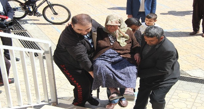 Yaşlı kadın sağlık görevlilerinin kollarında sandığa gitti