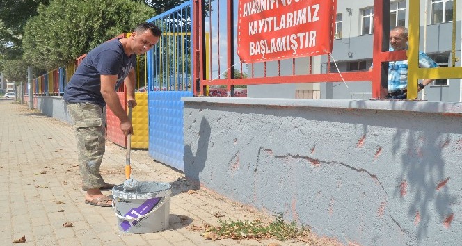 Okul müdürü elinde fırçayla okulu boyuyor