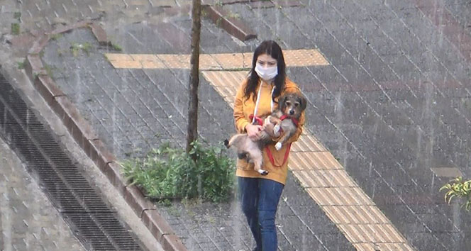 Şiddetli yağışa hazırlıksız yakalanınca köpeğini kucaklayıp koştu