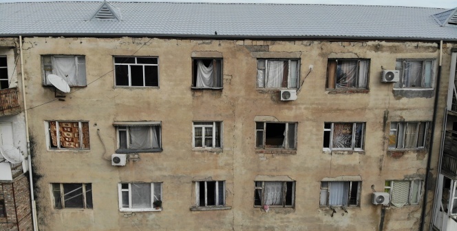 Gence’de füze saldırısı sonucu camları kırılan savaşzedeler kırılan camlarını naylon ve kilimle örttü