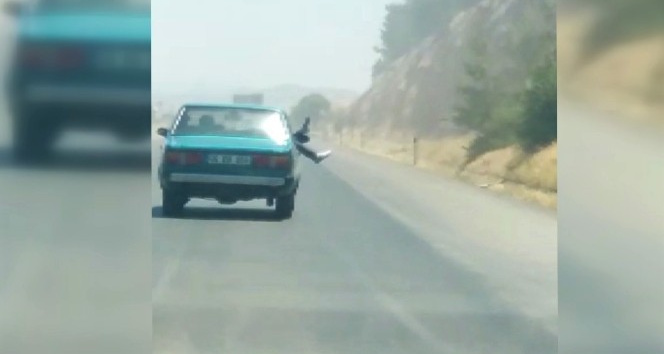 Bacaklarını otomobilin camından sarkıtarak yolculuk yaptı