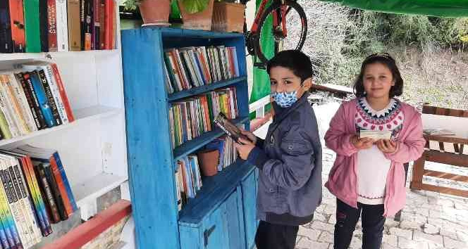 Evin bahçesine kurduğu kütüphanede mahallece kitap okuyorlar