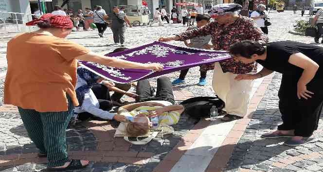 Kadınlar yerde yatan yaralıyı örtü ile güneşten korudu