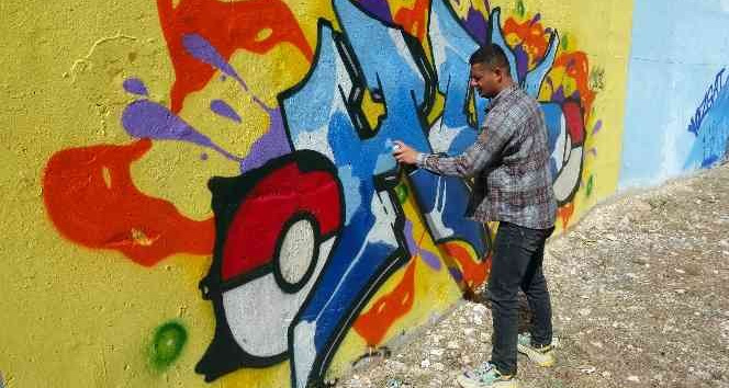 İlçenin gri duvarlarını grafiti ile renklendiriyor