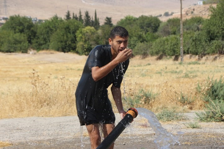 Mardin’de sıcaktan bunalan vatandaş tarım sulama hortumu ile serinledi 