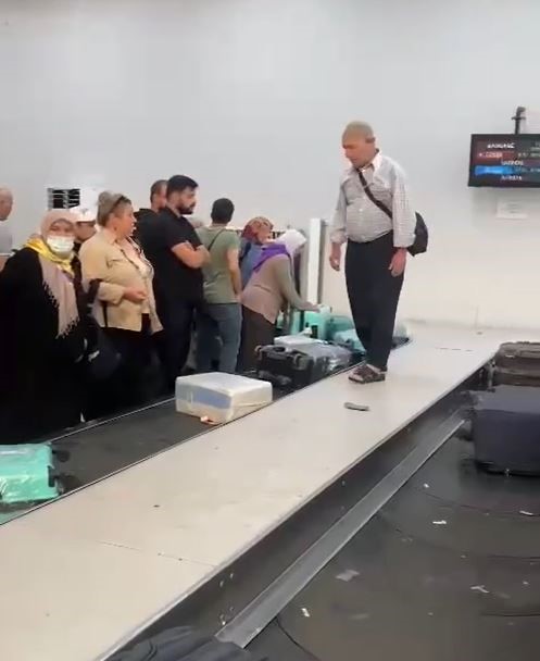Adana&rsquo;da hacdan d&ouml;nen vatandaşlar izdiham sonrası valizlerine bandın &uuml;zerine &ccedil;ıkarak ulaşmaya &ccedil;alıştı
