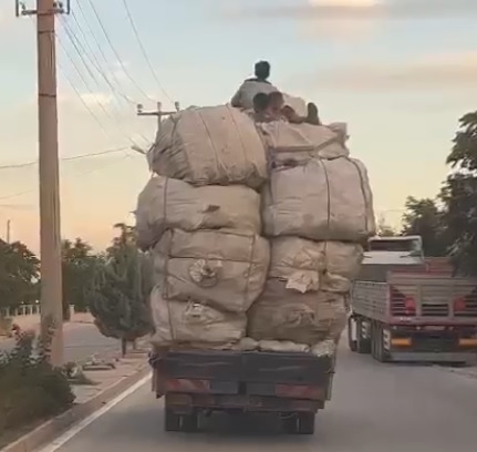 Kamyonetteki yükün üzerindeki çocukların elektrik tellerine çarpmamak için eğilerek gitmeleri kamerada