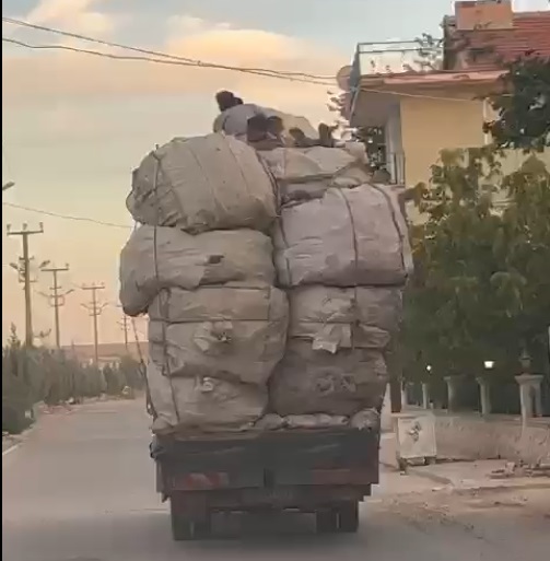 Kamyonetteki yükün üzerindeki çocukların elektrik tellerine çarpmamak için eğilerek gitmeleri kamerada
