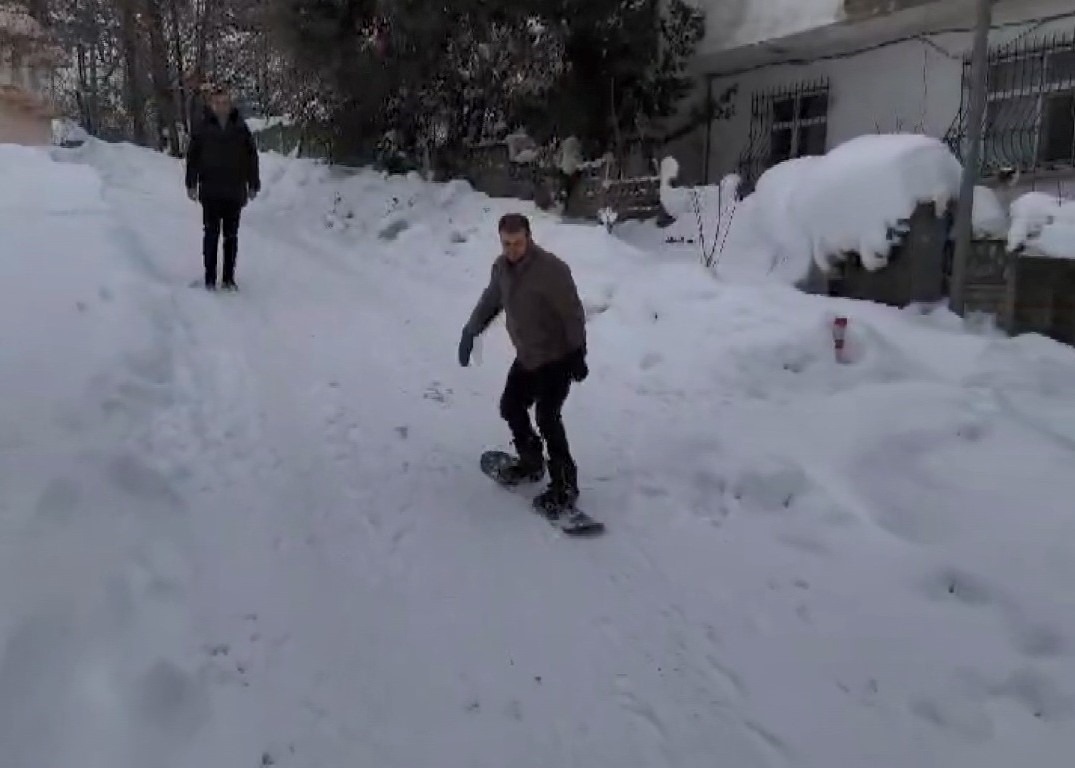 Doktordan karla kaplı sokaklarda &lsquo;snowboard&rsquo; g&ouml;sterisi
