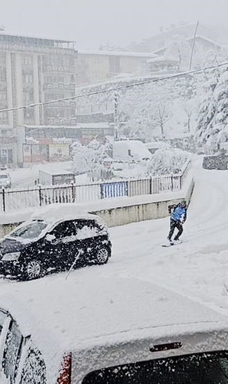 Karla kaplı yolda işine snowbordla kayarak gitti