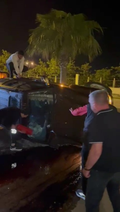 Devrilen otomobildekilerin çıkarılma anlarını film izler gibi izlediler