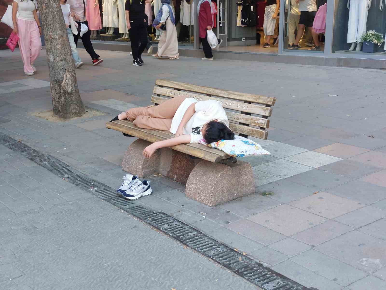 Sıcaktan bunalan genç gölgelik bankta yastıkla beraber uyudu