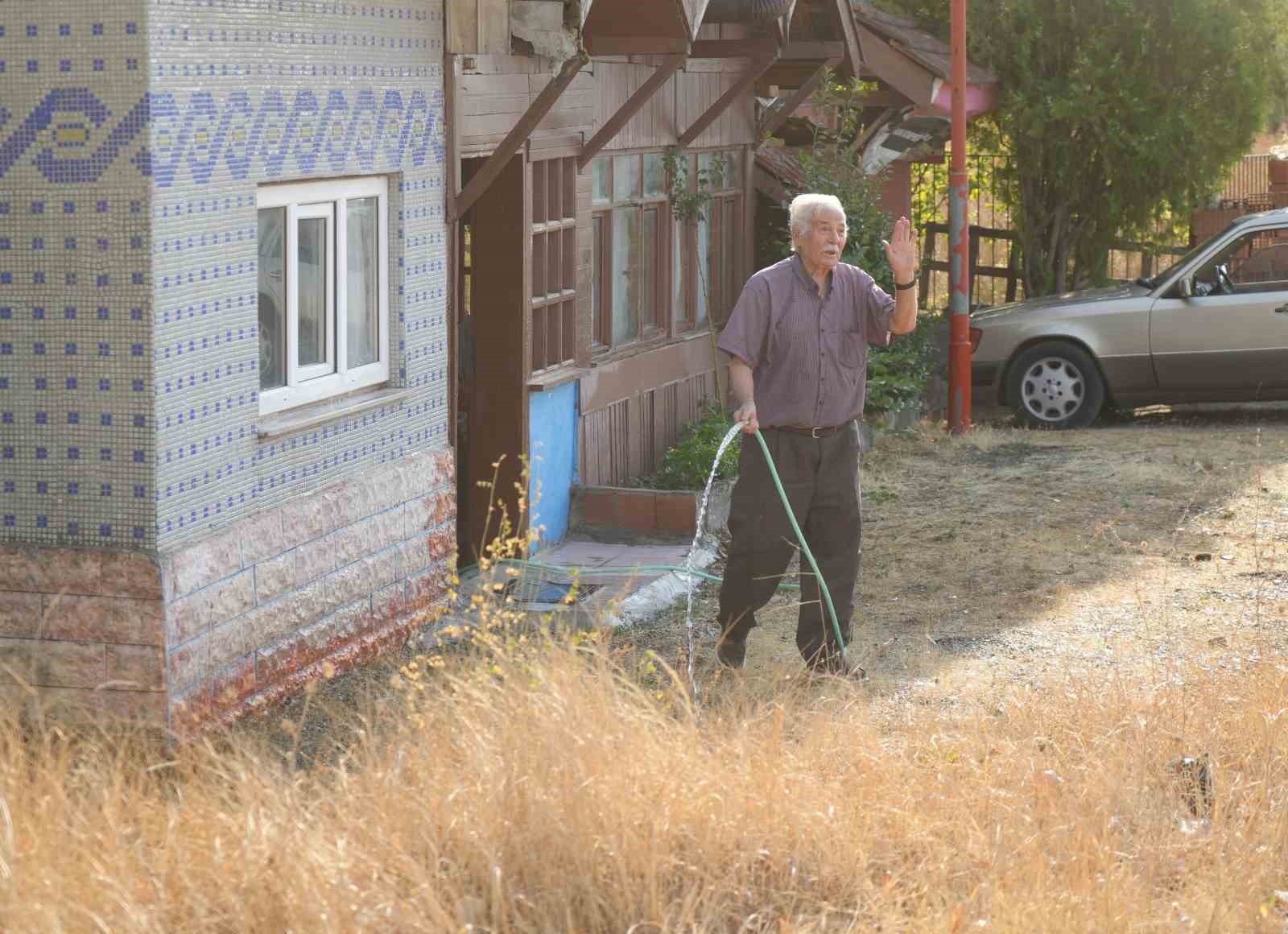 Elinde hortumla otları ıslatarak evini yangından korumaya &ccedil;alıştı
