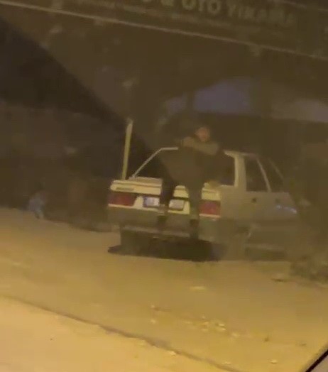 Adıyaman&rsquo;da tepki &ccedil;eken g&ouml;r&uuml;nt&uuml;: Seyir halindeki otomobilin bagaj kısmına oturarak ilerledi
