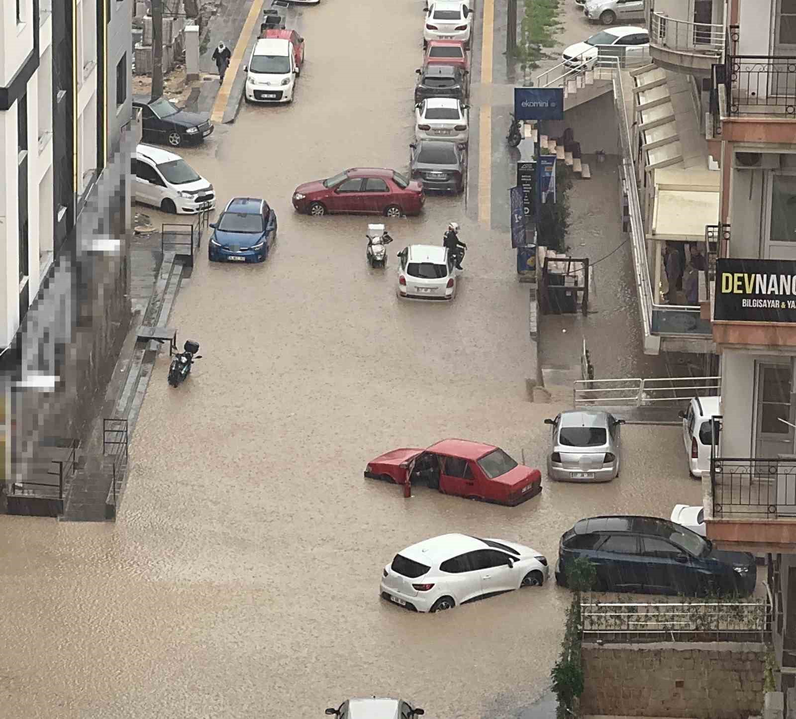 Yağmurda mahsur kalan motosikletli çareyi otomobilin üzerine çıkmakta buldu