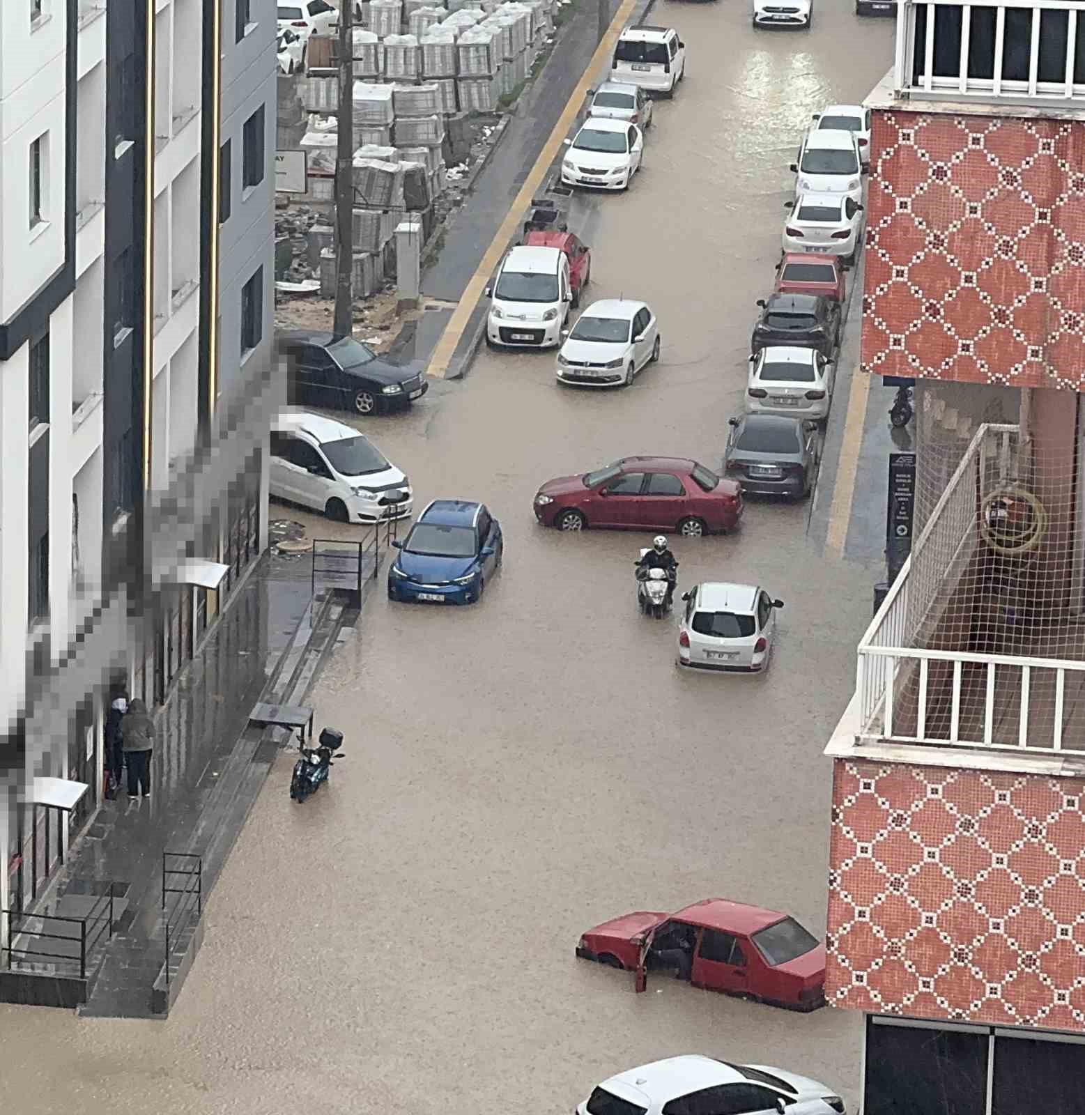 Yağmurda mahsur kalan motosikletli &ccedil;areyi otomobilin &uuml;zerine &ccedil;ıkmakta buldu
